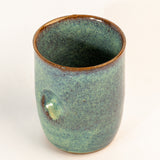 Green ceramic cup with brown rim on a white background