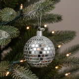 Silver disco ball ornament on a Christmas tree with lights.