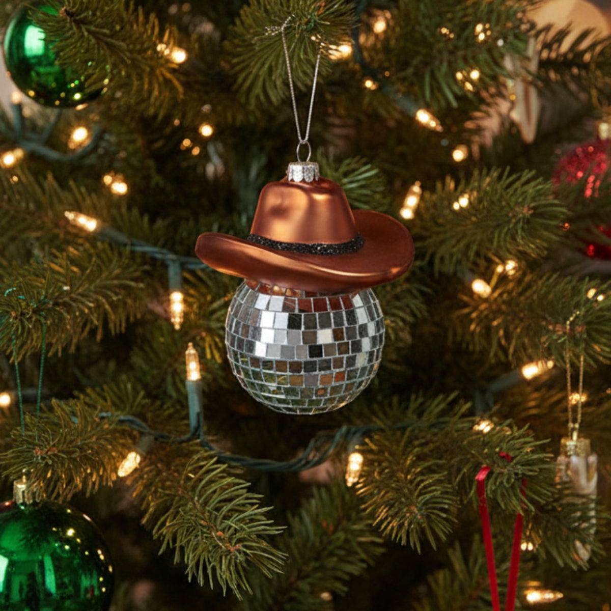 Decorative ornament with a disco ball and cowboy hat on a Christmas tree