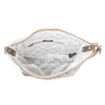 The interior of a shoulder bag shown open against a white background, featuring a white fabric lining with a black dotted circular pattern and tan leather trim.