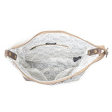 The interior of a shoulder bag shown open against a white background, featuring a white fabric lining with a black dotted circular pattern and tan leather trim.
