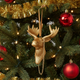Gold deer head ornament on a Christmas tree with red ornaments and lights.