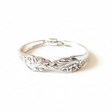 Silver bracelet with intricate design on a light wooden surface