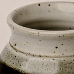 Close-up of a ceramic pot with speckled texture on a beige background