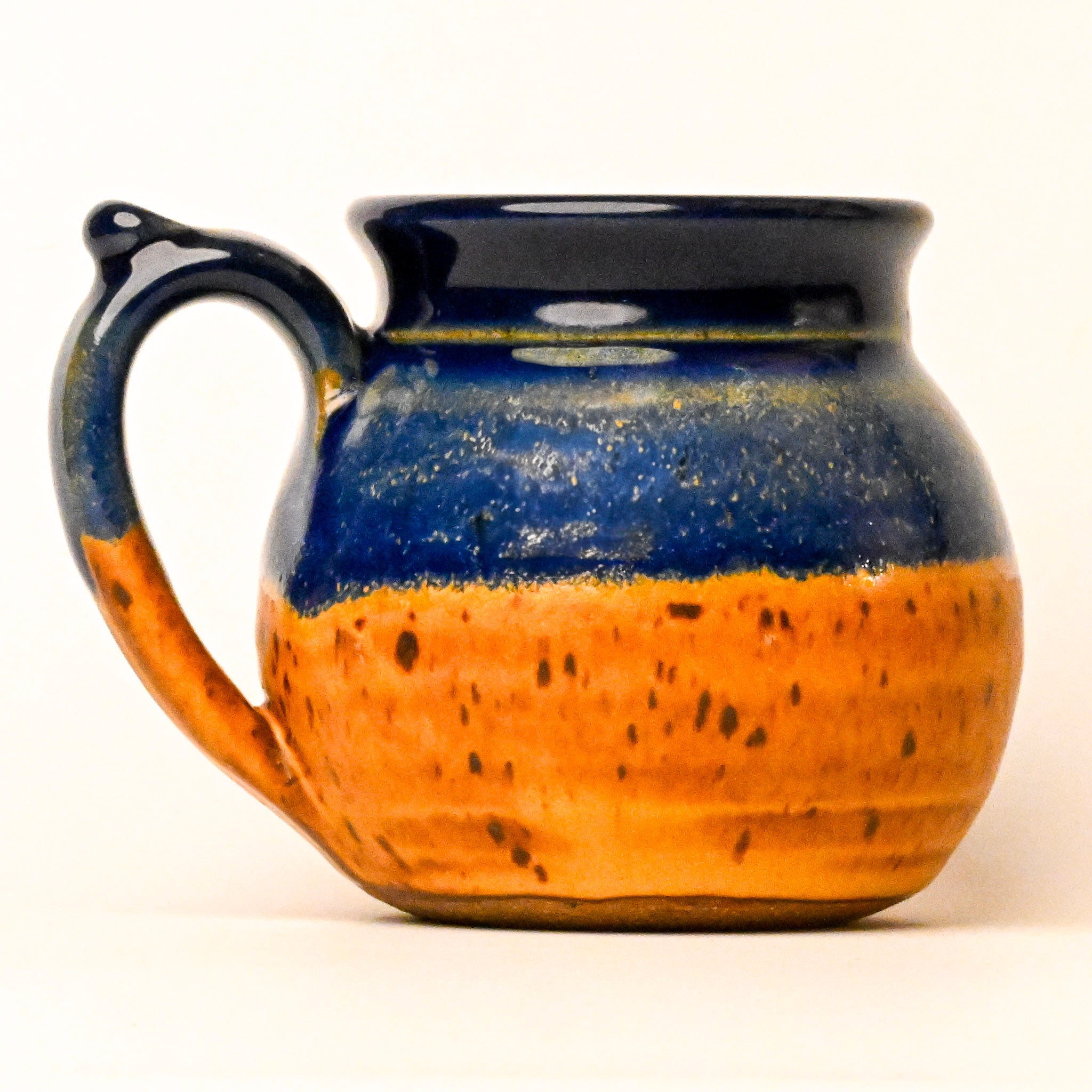 Ceramic mug with blue and orange glaze on a white background
