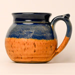 Ceramic mug with blue and orange glaze on a beige background