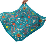 Colorful fabric with animal and floral patterns held by hands on a white background