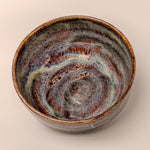 Ceramic bowl with swirling brown and blue pattern on a beige background