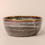 Ceramic bowl with speckled glaze on a beige background