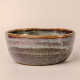 Ceramic bowl with speckled glaze on a beige background