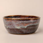 Ceramic bowl with a speckled glaze on a beige background
