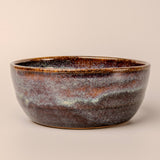 Ceramic bowl with a speckled glaze on a beige background