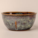 Stoneware bowl with a speckled glaze on a beige background