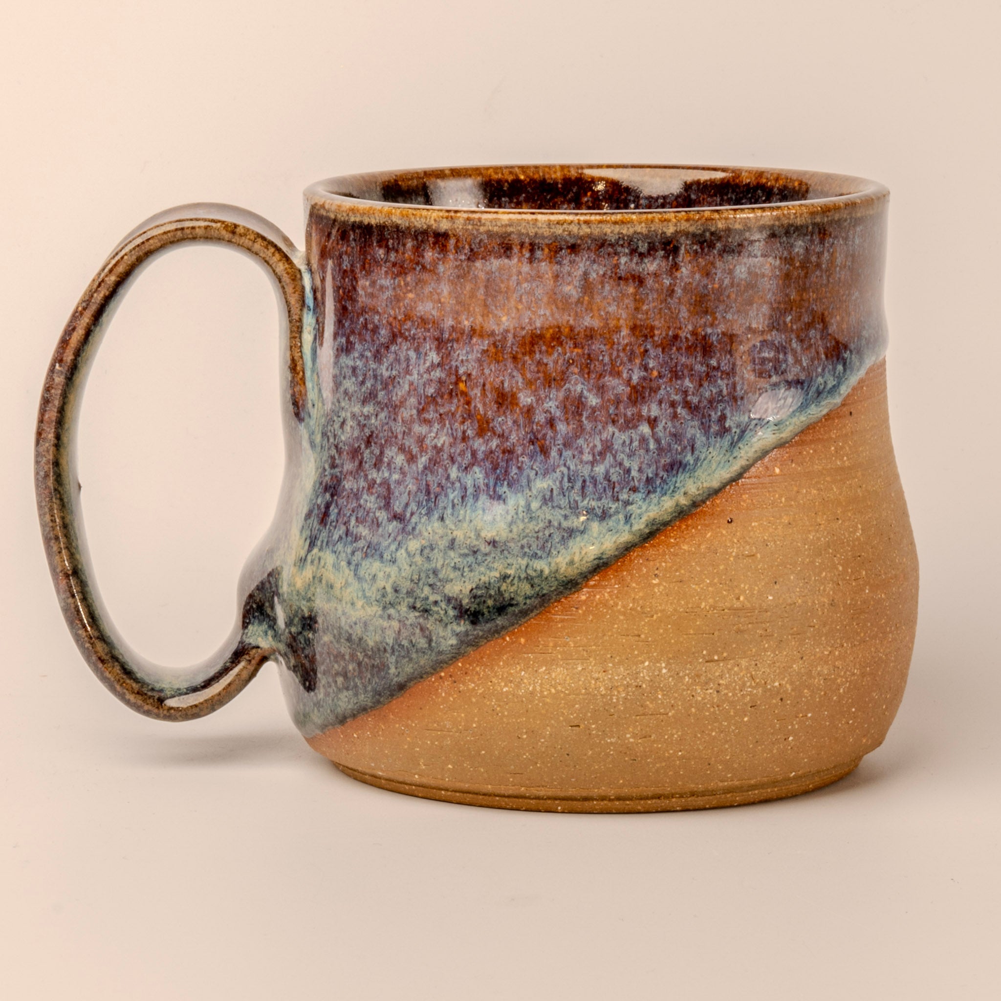 Ceramic mug with multicolored glaze on a beige background