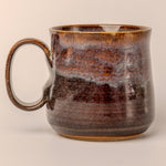 Brown ceramic mug with a textured surface on a beige background