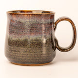 Ceramic mug with brown and black speckled glaze on a white background