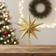 Gold star-shaped Christmas tree topper on a wooden surface with festive background