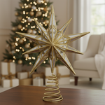 Decorative gold star tree topper on a table with a Christmas tree and gifts in the background.