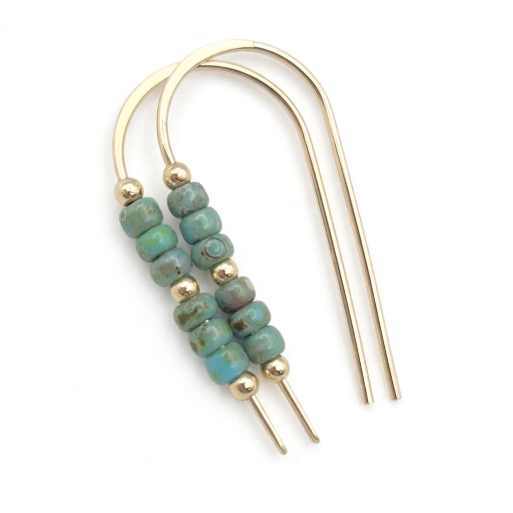 A pair of gold-toned U-shaped hair claw earrings with a central cluster of round turquoise-blue beads separated by small gold spacer beads, shown on a plain white background.