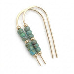 A pair of gold-toned U-shaped hair claw earrings with a central cluster of round turquoise-blue beads separated by small gold spacer beads, shown on a plain white background.