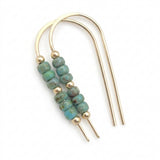 A pair of gold-toned U-shaped hair claw earrings with a central cluster of round turquoise-blue beads separated by small gold spacer beads, shown on a plain white background.