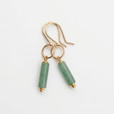A pair of gold-tone dangle earrings with cylindrical light green stone beads, displayed on a white background
