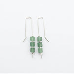 A pair of silver drop earrings with three green faceted beads on each earring, displayed on a white background