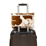 Brown and white cow print luggage cover on a suitcase with a white background