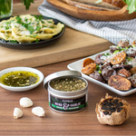Table with food, herbs, and a container of Olivelle herb and garlic seasoning.