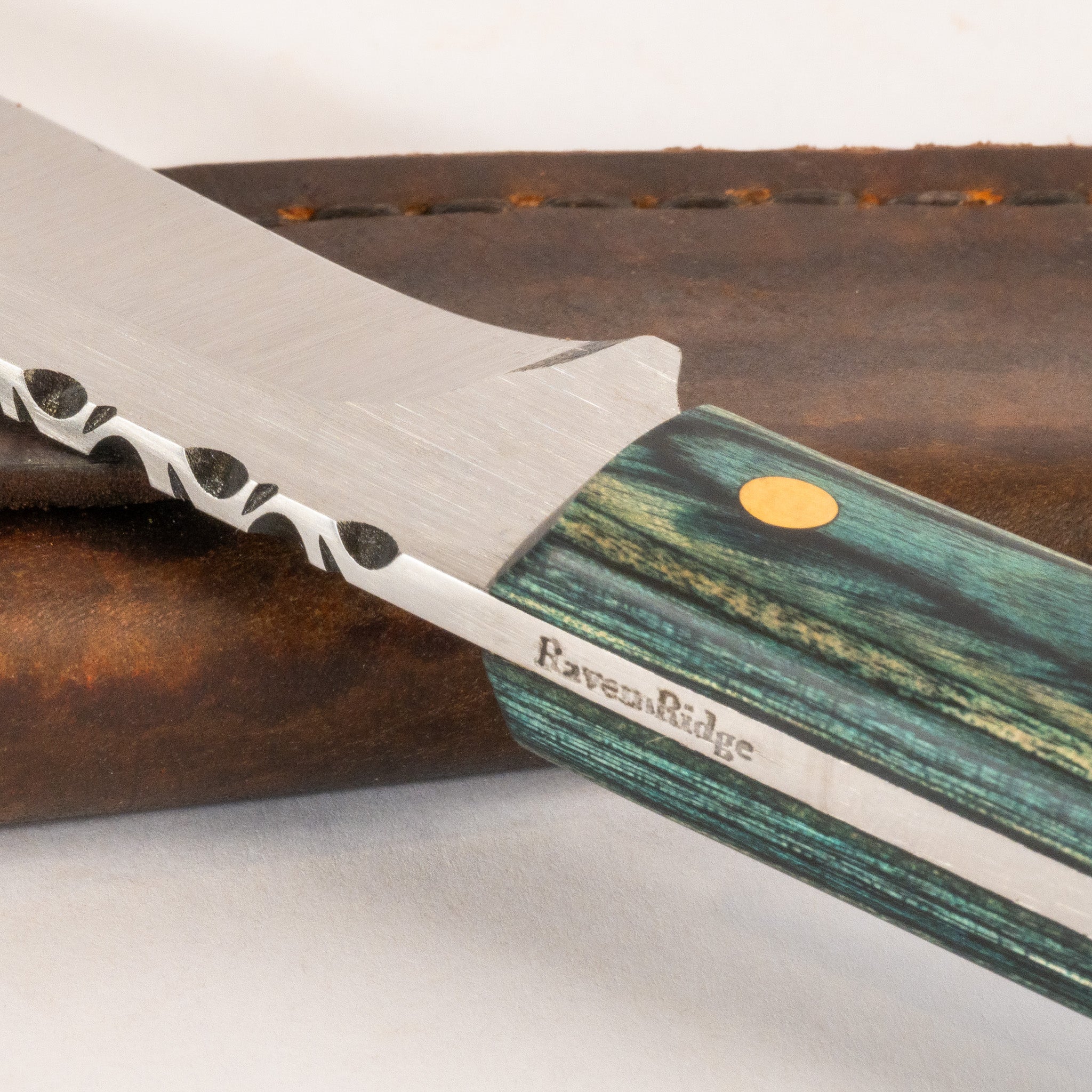 close up of hand crafted knife with wooden handle and leather sheath on white background