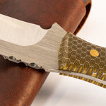 knife with steel blade and honeycomb patterned handle with a leather sheath on a white background