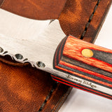 Close-up of a knife with a wooden handle and leather sheath, featuring the brand 'Raven Ridge'.