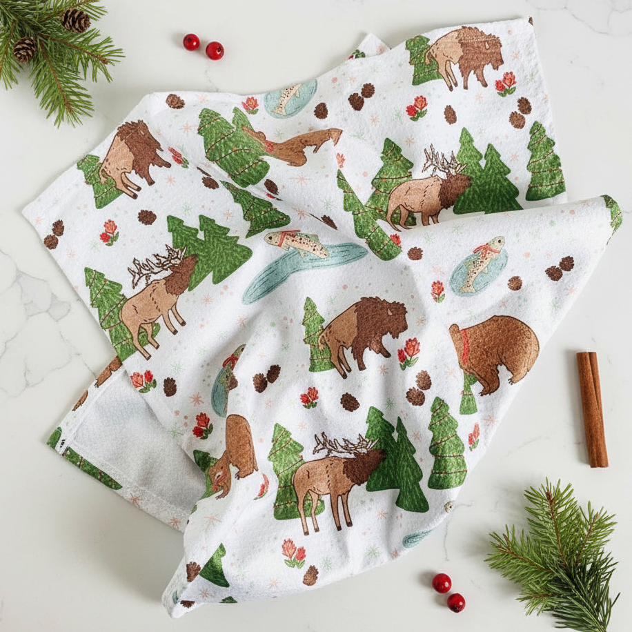 Kitchen towel with forest animal pattern on a white surface with pine branches and berries.