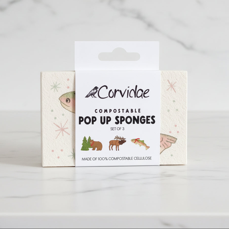 Packaging of Corvidae compostable pop-up sponges on a wooden surface