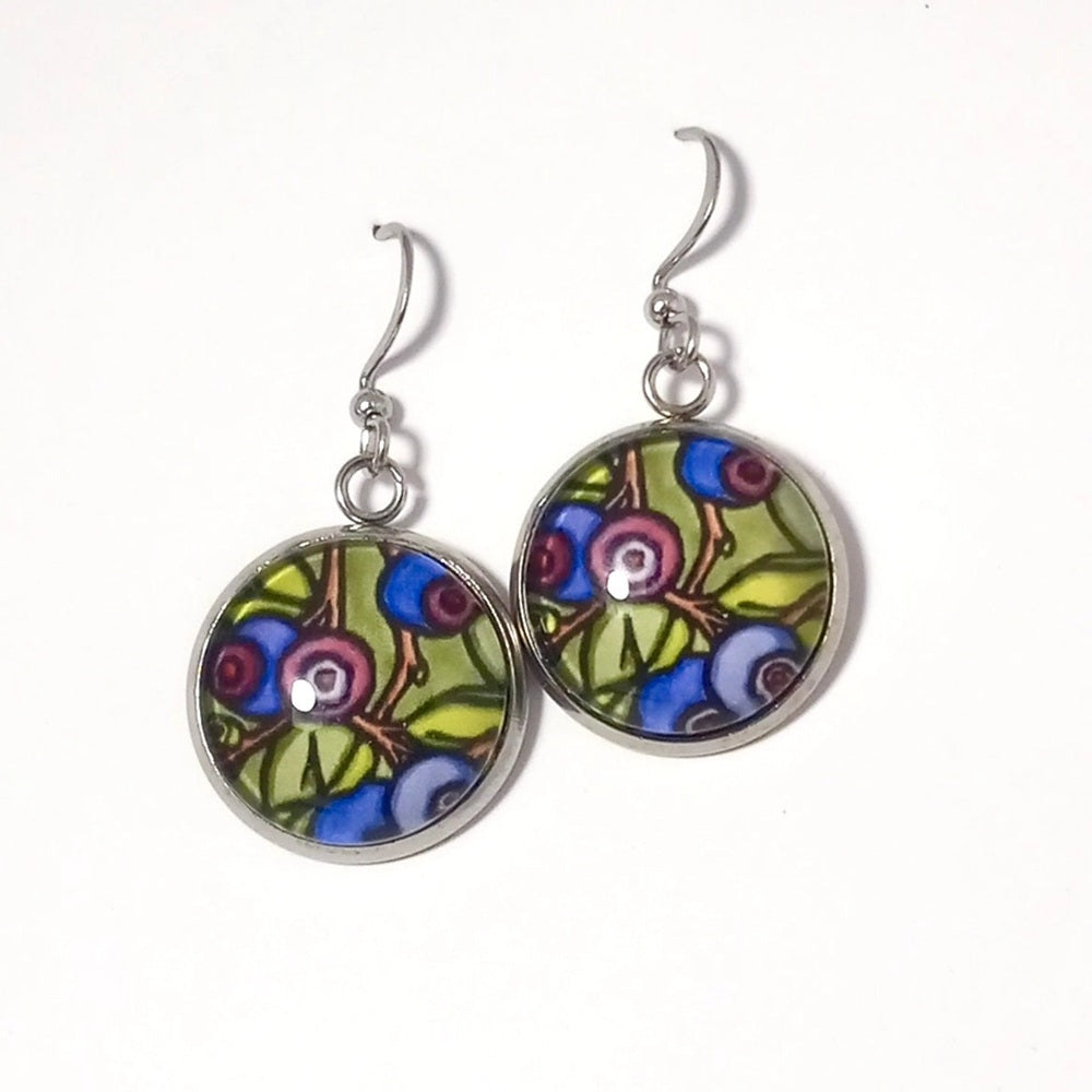 A pair of silver-tone dangle earrings with round glass cabochons featuring a colorful floral and berry pattern in green, blue, purple, and pink, shown on a plain white background.