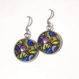 A pair of silver-tone dangle earrings with round glass cabochons featuring a colorful floral and berry pattern in green, blue, purple, and pink, shown on a plain white background.