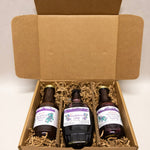 Three bottles of huckleberry product in an open cardboard box with a plain background