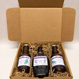 Three bottles of huckleberry product in an open cardboard box with a plain background