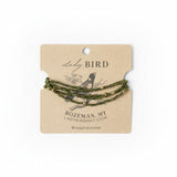 Green beaded bracelet on a 'Lady Bird' branded card with a blurred natural background