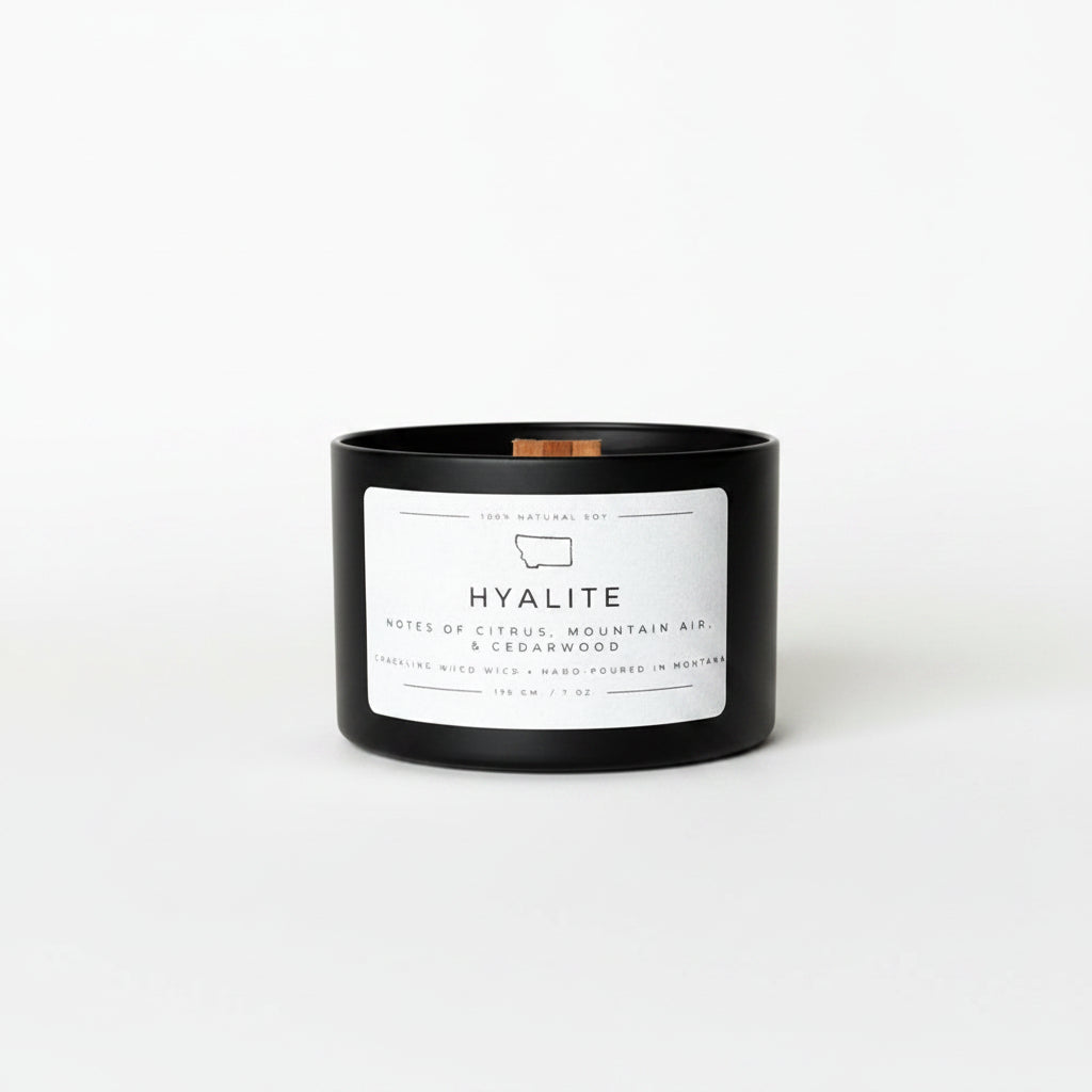 Black candle with a white label on a white surface and background