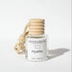 A small glass bottle candle with a white label reading 'GALLATIN CANDLE CO' and 'Hyalite', topped with a stacked beige wooden stopper and a braided beige cord with small gold beads, photographed on a light gray background.