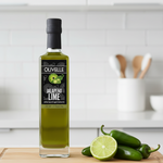 Bottle of Olivelle Jalapeno Lime white balsamic vinegar on a kitchen counter with jalapenos and a lime.