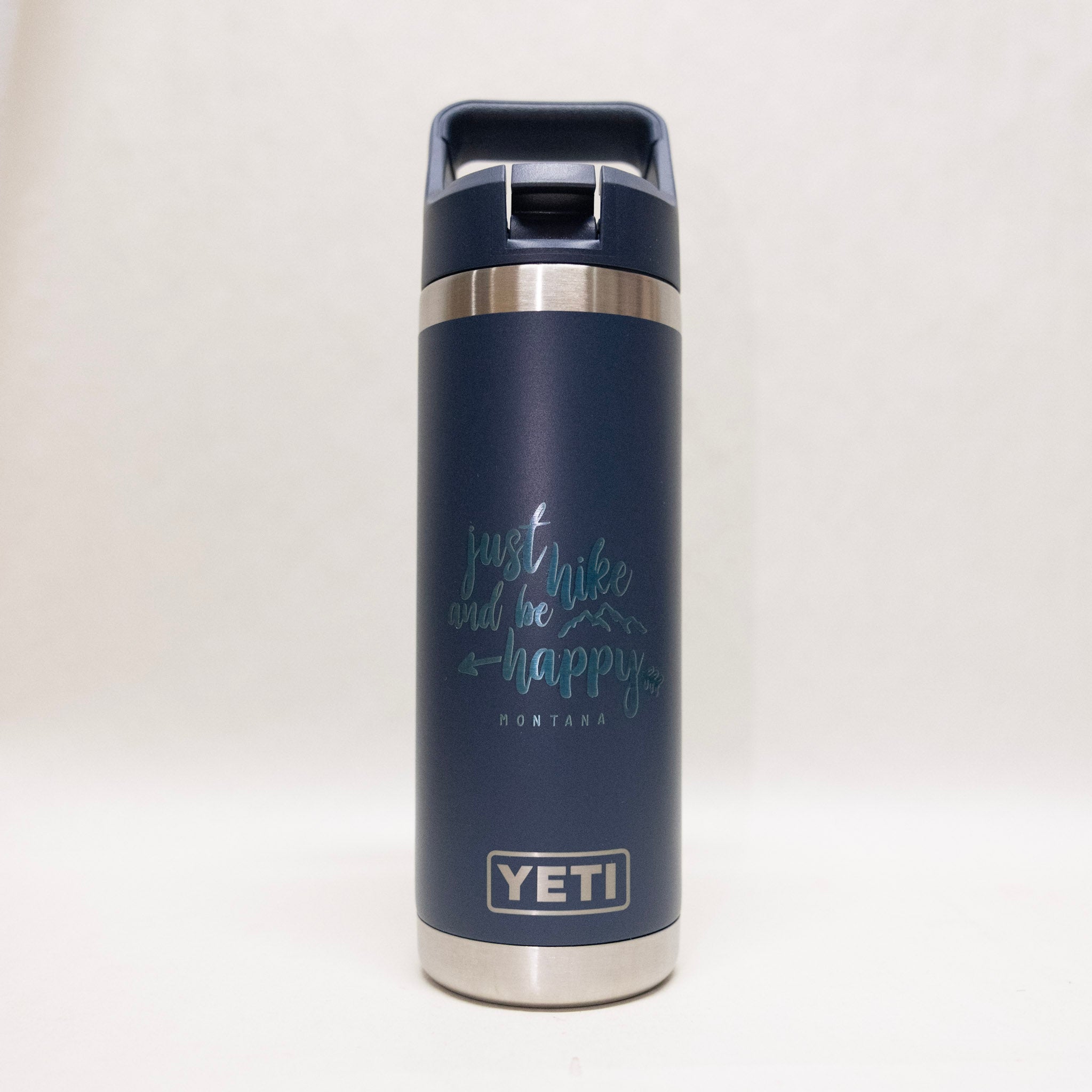 Navy blue YETI insulated bottle with 'Just hike and be happy' text on a white background