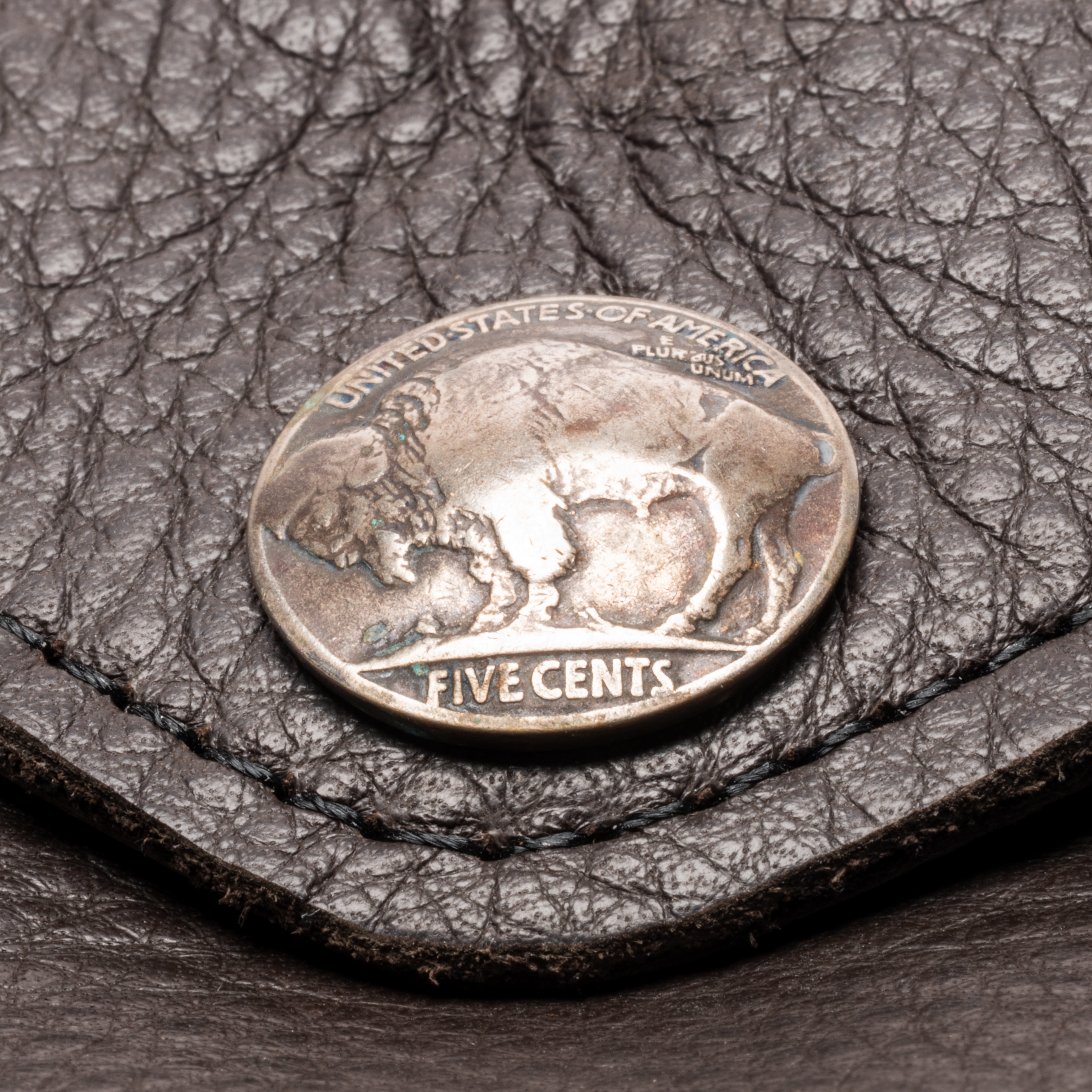 A vintage silver US five-cent coin resting on a textured dark brown leather surface.
