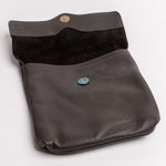 A dark brown pebbled leather pouch with a dark brown suede-like interior lining, featuring two metal snap buttons (one gold-toned, one blue-toned) and photographed on a clean white background.