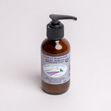 An amber glass pump bottle of 'Cream of Magnesium' moisturizing cream by Wild Sky Lavender Farms, featuring a black pump and a white label with purple and blue accents, set against a plain white background.
