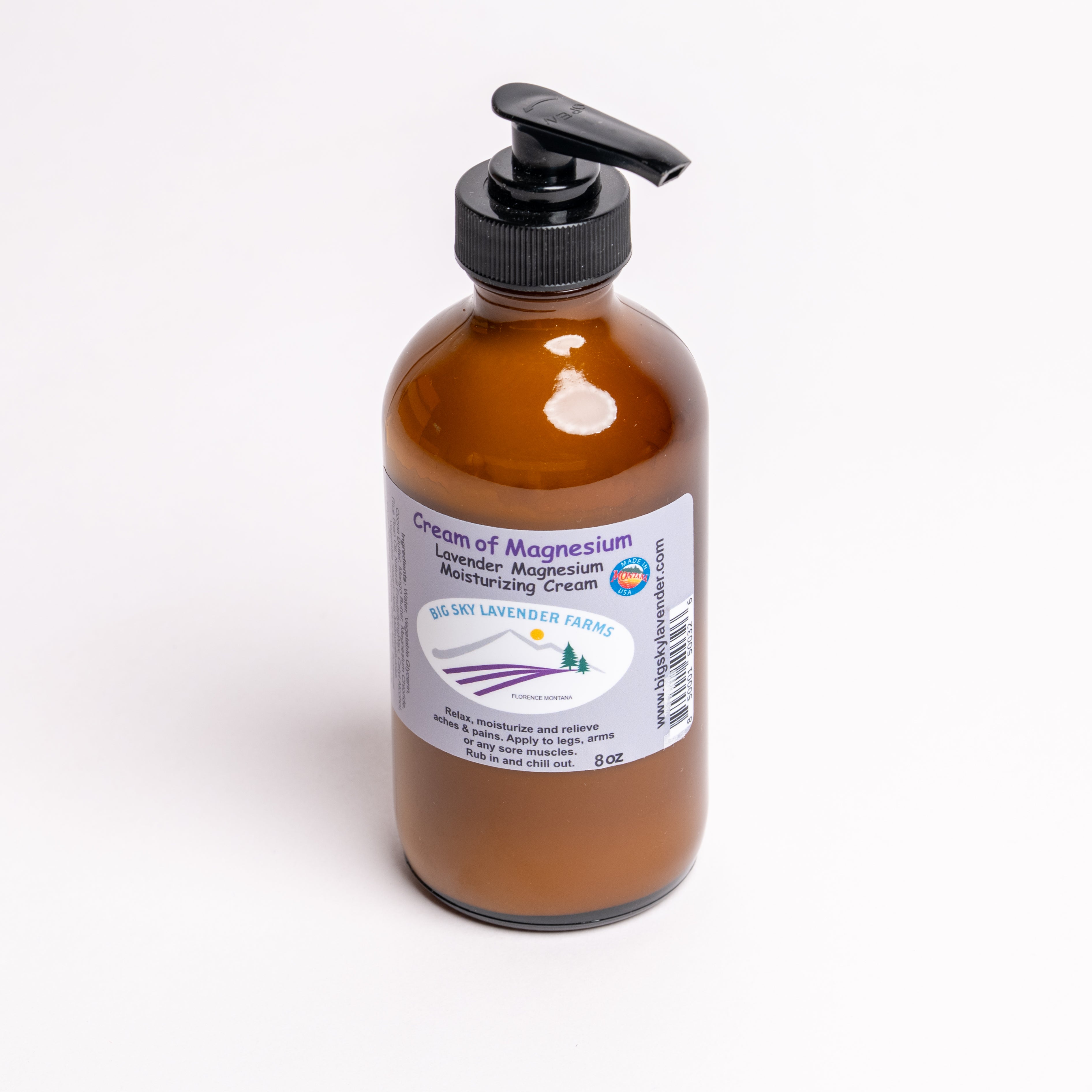 An amber glass pump bottle of Big Sky Lavender Farms Cream of Magnesium moisturizing cream, featuring a black pump dispenser and a white label with purple and blue text, set against a plain white background.