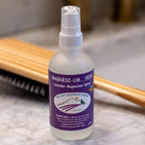 Bottle of Magnesi-UM spray with a purple label on a marble surface.