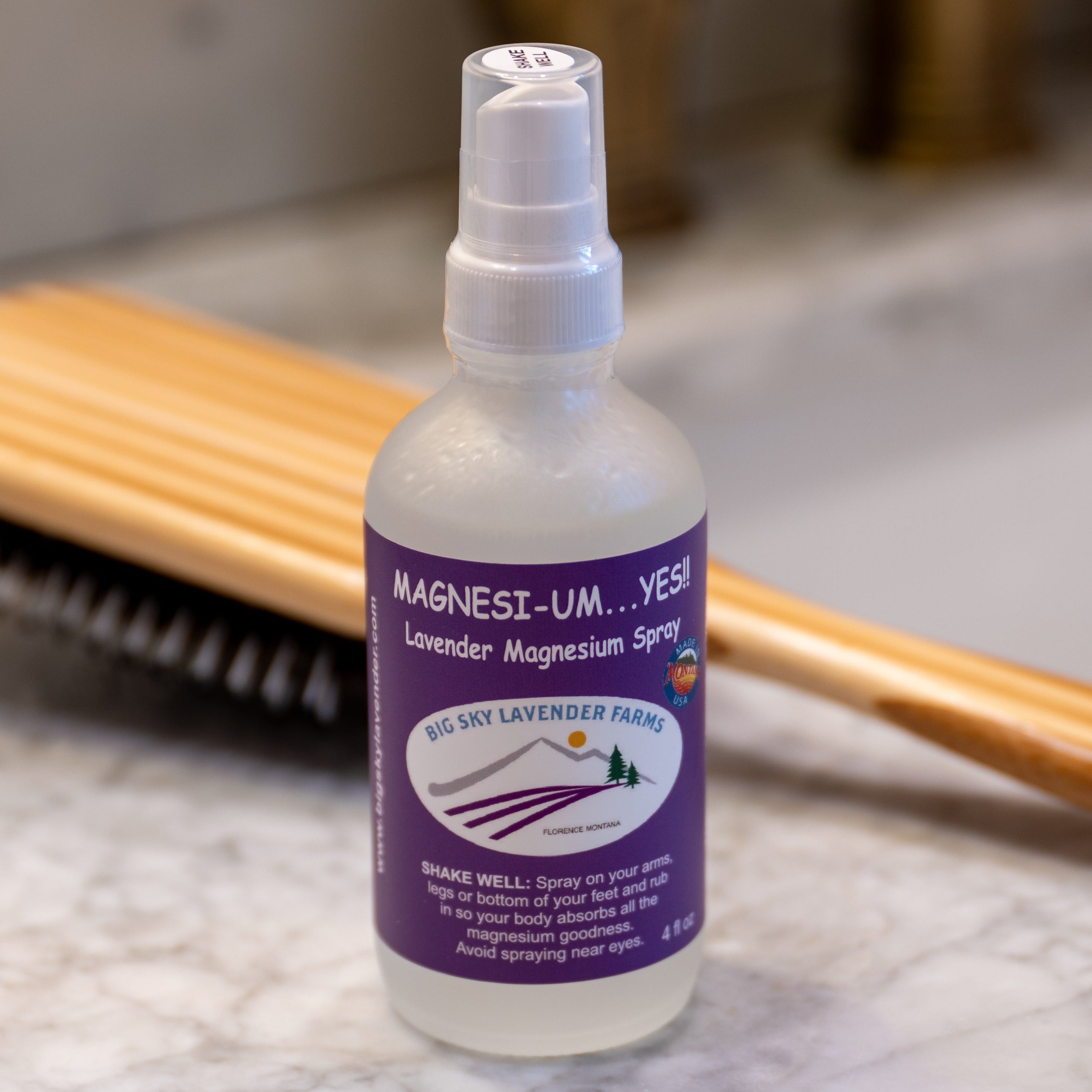 Bottle of Magnesi-UM spray with a purple label on a marble surface.