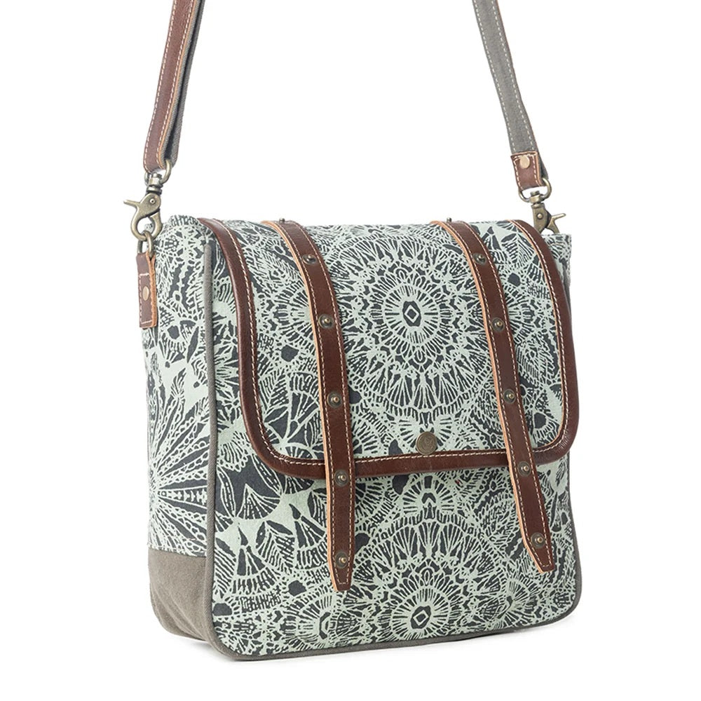 A rectangular crossbody bag with a gray and white mandala patterned canvas body, brown leather straps, and a matching gray shoulder strap, shown on a plain white background.